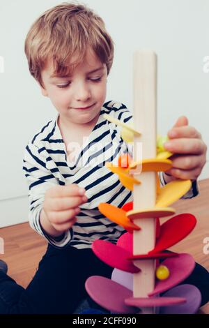 Blonde cute boy playing with waldorf sounding tower with marbles Stock Photo