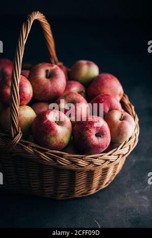 Fresh red apples on dark table and in a wicker basket on dark background Stock Photo