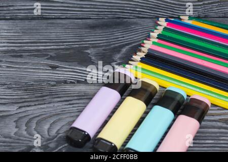 Colored pencils and colored markers. On brushed pine boards painted black and white. Stock Photo