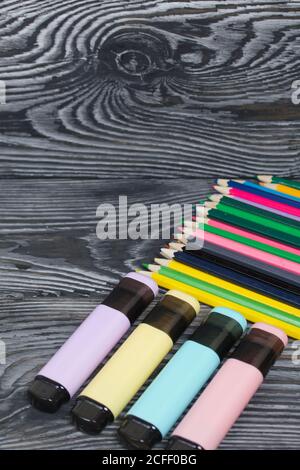 Colored pencils and colored markers. On brushed pine boards painted black and white. Stock Photo