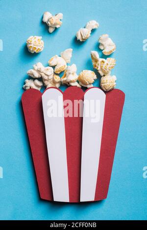 Silhouette of a stripped popcorn box made of cardboard with real popcorn on blue background Stock Photo