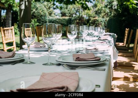 Outdoor rustic celebration table with cutlery and glasses Stock Photo