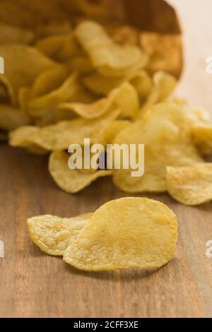 Crispy potato chips placed on wooden table in kitchen Stock Photo