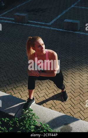 Young blonde Woman doing stretching exercises after a running session Stock Photo