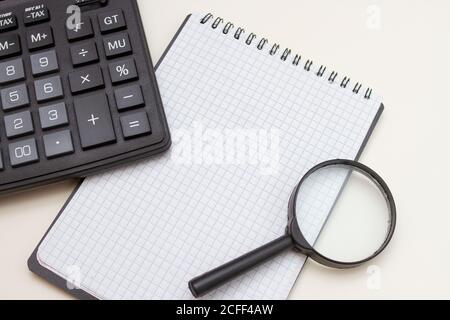 Calculator, blank note book and magnifier on a white background. Accountant Tools for Business Stock Photo
