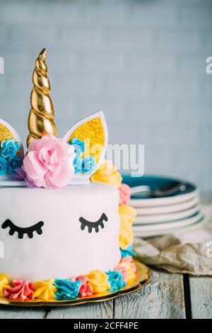 Tasty sweet festively decorated cake with sleeping unicorn on wooden table Stock Photo