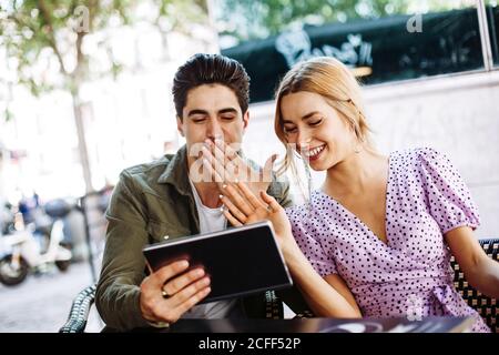 Cheerful young attractive couple using tablet outdoors in town in warm day Stock Photo