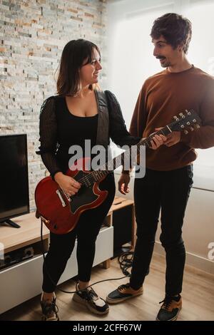 man teaching Woman to play guitar at home Stock Photo