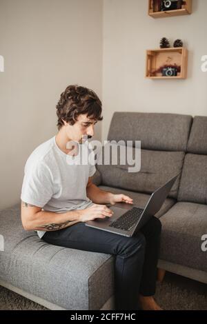 Side view of concentrated male entrepreneur using laptop while working on remote project at home Stock Photo