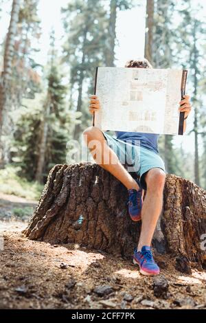 young man holding map and checking for road sitting on the woods Stock Photo