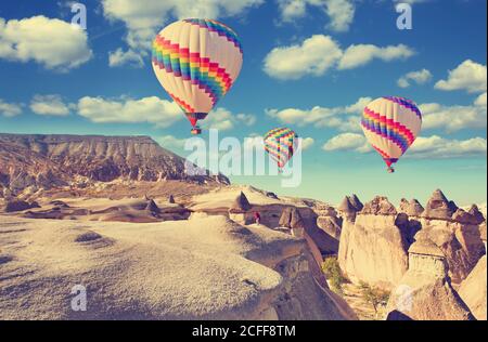 Vintage photo of hot air balloon flying over rock landscape at Cappadocia Turkey. Stock Photo