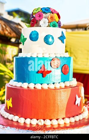 Very unusual colorful wedding cake, decorated with flowers and butterflies, placed on a table, for use at a beach wedding in the Philippines, Asia Stock Photo