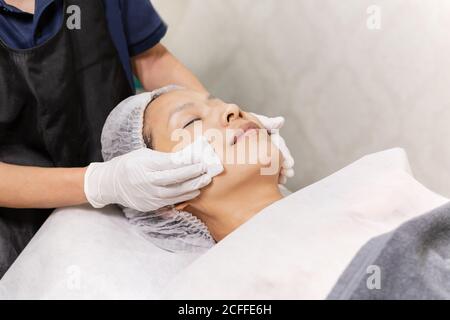 Beautician cleaning female face with cotton pad skin care spa conceptual. Stock Photo