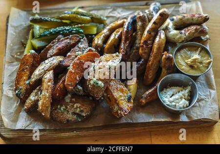 Viennese sausages with fried potatoes and garlic on a wooden plate around wooden background. Creative composition. Healthy lifestyle concept. Stock Photo