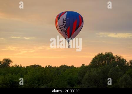 RYAZAN, RUSSIA - AUGUST 16, 2020: Hot air balloon passing over trees with beautiful evening sky as a background