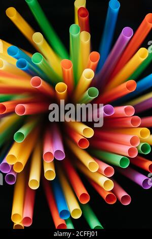 From above multicolored plastic straws for drinking cocktails on black background