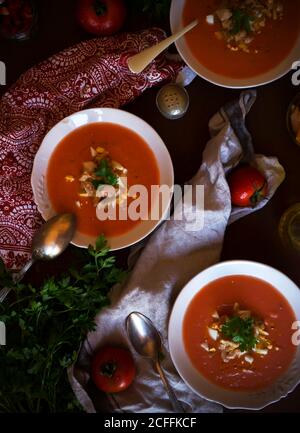 From above bowls of delectable tomato soup with parsley placed near napkins on table Stock Photo