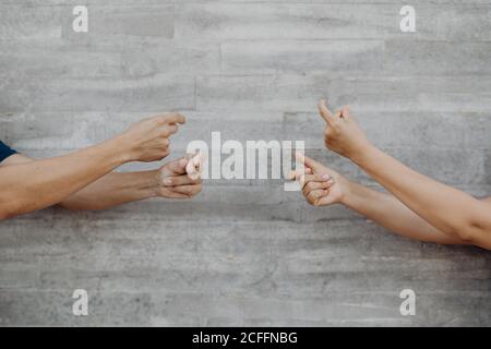 Tanned strong hands of crop man and Woman gesturing with music on grey wall Stock Photo