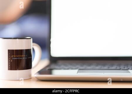 Modern netbook with blank screen placed on table together with mug of hot drink with picture of computer code Stock Photo