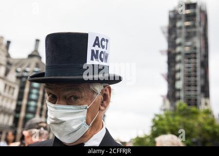 London, UK. 3rd September, 2020. A climate activist from Extinction Rebellion wearing a top hat bearing the words ‘Act Now’ attends a ‘Carnival of Corruption’ protest against the government’s facilitation and funding of the fossil fuel industry. Extinction Rebellion activists are attending a series of September Rebellion protests around the UK to call on politicians to back the Climate and Ecological Emergency Bill (CEE Bill) which requires, among other measures, a serious plan to deal with the UK’s share of emissions and to halt critical rises in global temperatures and for ordinary people to Stock Photo