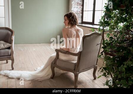 Gorgeous Woman with red lips in white dress sitting on armchair Stock Photo