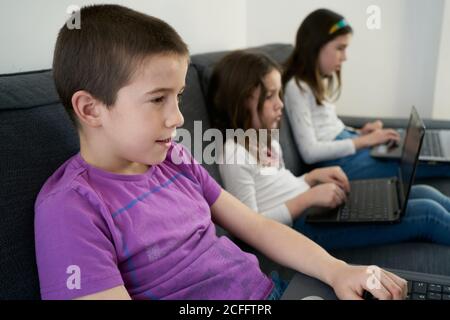Group of children using laptops while sitting on sofa at home Stock Photo