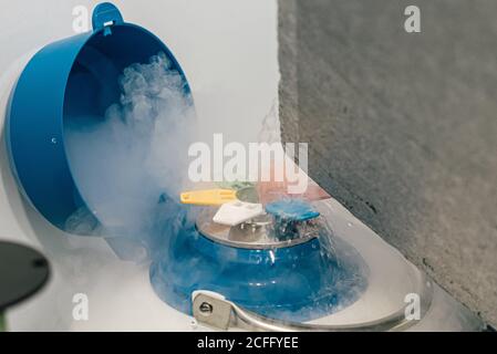 Nitrogen liquid splashing from a cryogenic tank container with frozen egg cells and embryos in fertility clinic Stock Photo