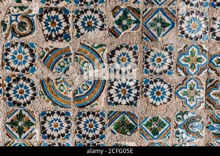 Background of ornamental elements of mosaic tiles on weathered stone surface in city Stock Photo
