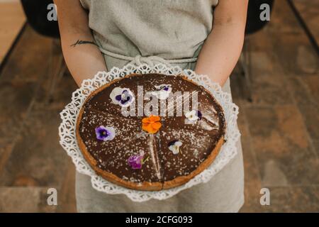 From above tasty appetizing cake festively decorated with bright flowers in hands of woman Stock Photo