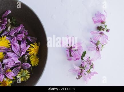 Yellow and mauve flowers in bowls on table Stock Photo