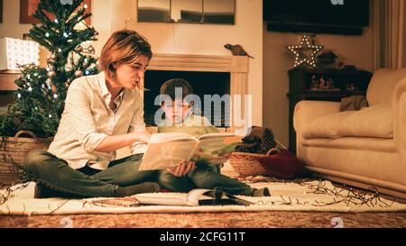 Mother reading book with son on Christmas eve Stock Photo