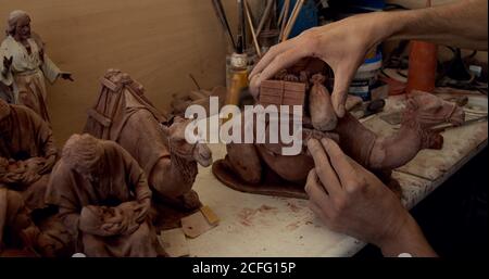 Crop person smoothing statuette of decorative clay camel on table in pottery Stock Photo