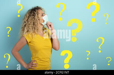 Blonde girl has doubt about covid19 corona virus. Cyan background. Stock Photo