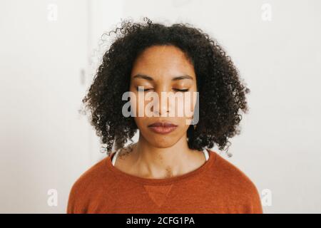 Close-up portrait of african american attractive young Woman meditating with closed eyes against white background Stock Photo