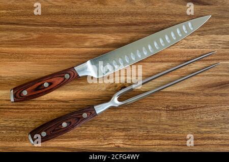 Photograph of knife and fork carving set on a wood cutting board Stock Photo