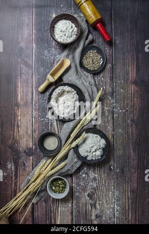 Flat lay of assorted types of bread flour and additives on rustic wooden surface with wheat Stock Photo
