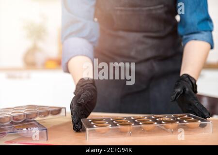Chef or chocolatier Shakes chocolate molds for sweets Stock Photo