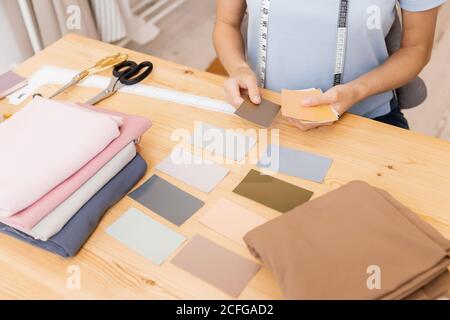 Seamstress young woman selects color layout for choosing fabrics and sewing clothes Stock Photo