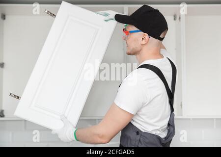 Kitchen installation man. Worker assembling furniture cabinet hinge Stock Photo