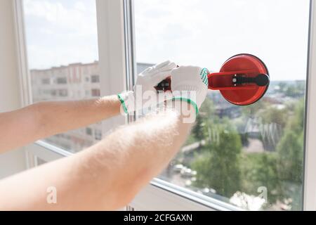 Worker man installs upvc plastic windows using suction cup Stock Photo