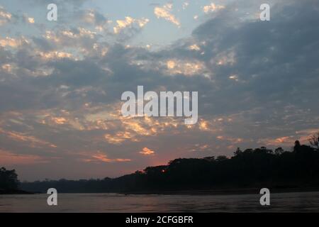 the sun rising over the Amazon rainforest and the Tambopata River in Madre de Dios, Peru Stock Photo