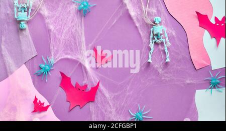 Split Halloween panoramic paper background with red paper buts, skeletons, spider web and spiders on pink, purple and white abstract background. Creat Stock Photo