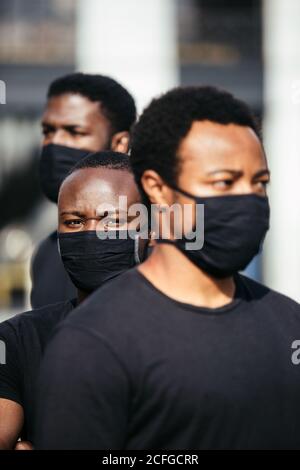 Black men on street holding masks. One of the is looking at camera with serious expression Stock Photo