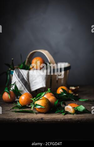 Ripe orange mandarins and basket with towel on rough wooden table Stock Photo