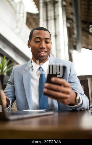 man using smartphone sitting at table Stock Photo