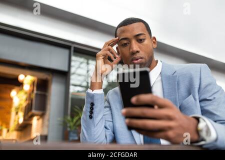 man using smartphone sitting at table Stock Photo