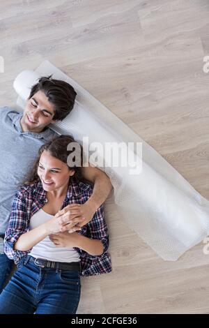 Young couple laying together on floor with carton boxes holding hands and looking at each other Stock Photo
