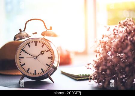alarm clock is on the ground. A paper, hat and flower near the clock. Stock Photo