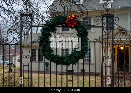 A Christmas Wreath With a Red Ball Hanging on an Ornamenta Black Fence Stock Photo