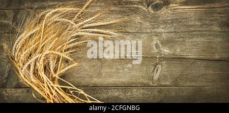 Golden spikes on wooden table background. Close up of ripe ears of barley plant. Top view and copy space for your advertising text message. Stock Photo